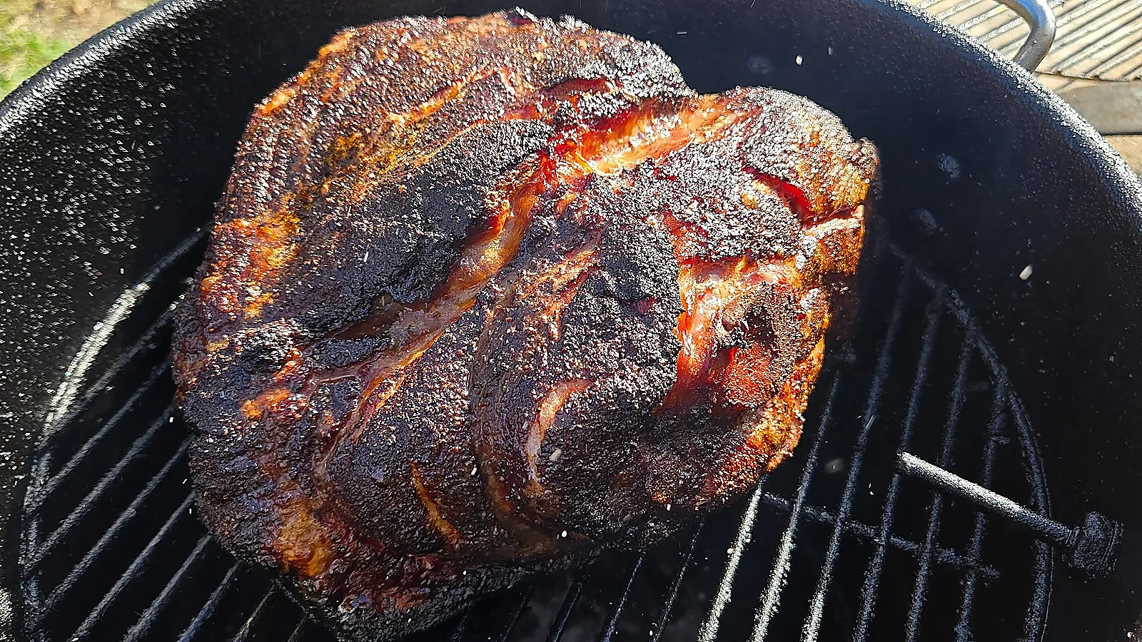 Smoked pork butt with deep bark on smoker for pulled pork